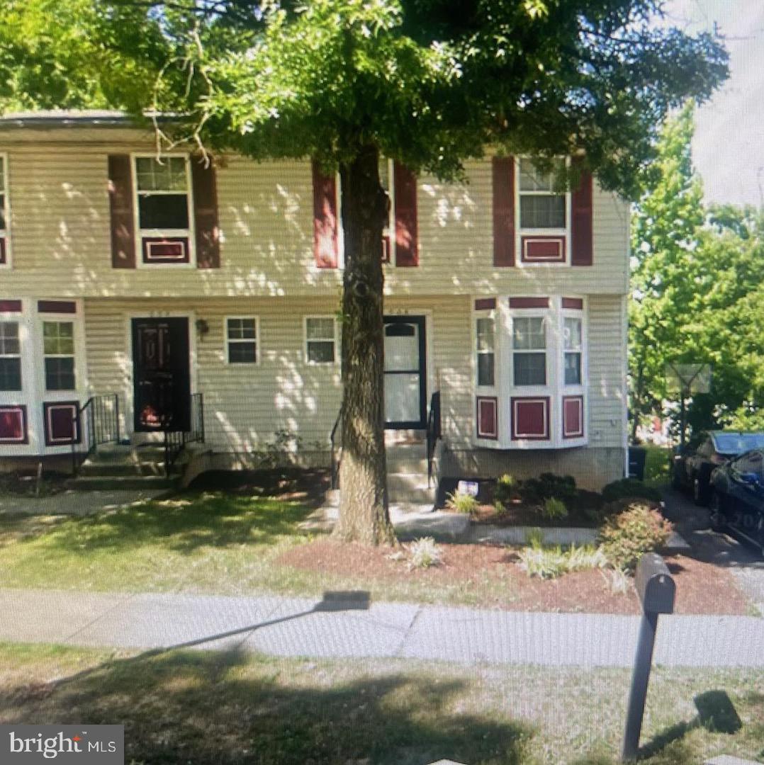 a view of a brick house with many windows plants and large tree