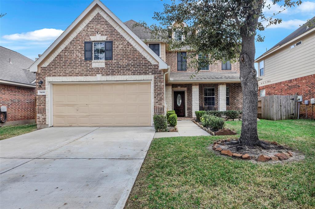 Inviting front view showcasing the home's striking brick and stone elevation, wide driveway leading to a 2-car garage, and freshly maintained landscaping for a warm and welcoming first impression.