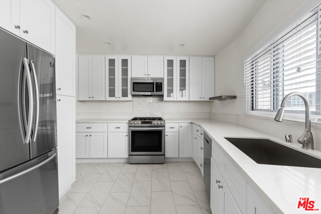 a kitchen with stainless steel appliances granite countertop a refrigerator sink and stove