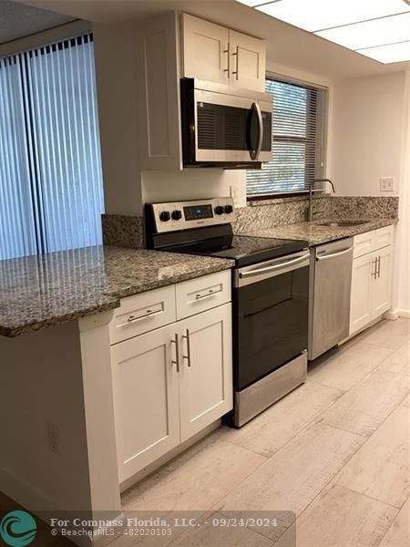 a kitchen with stainless steel appliances granite countertop a stove top oven a sink and dishwasher