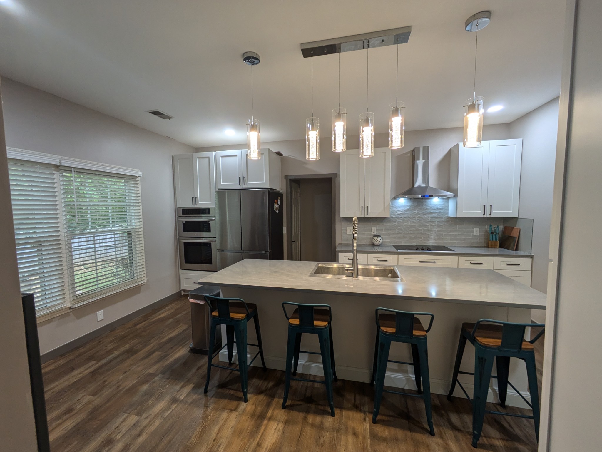 a kitchen with stainless steel appliances granite countertop a kitchen island hardwood floor and a sink