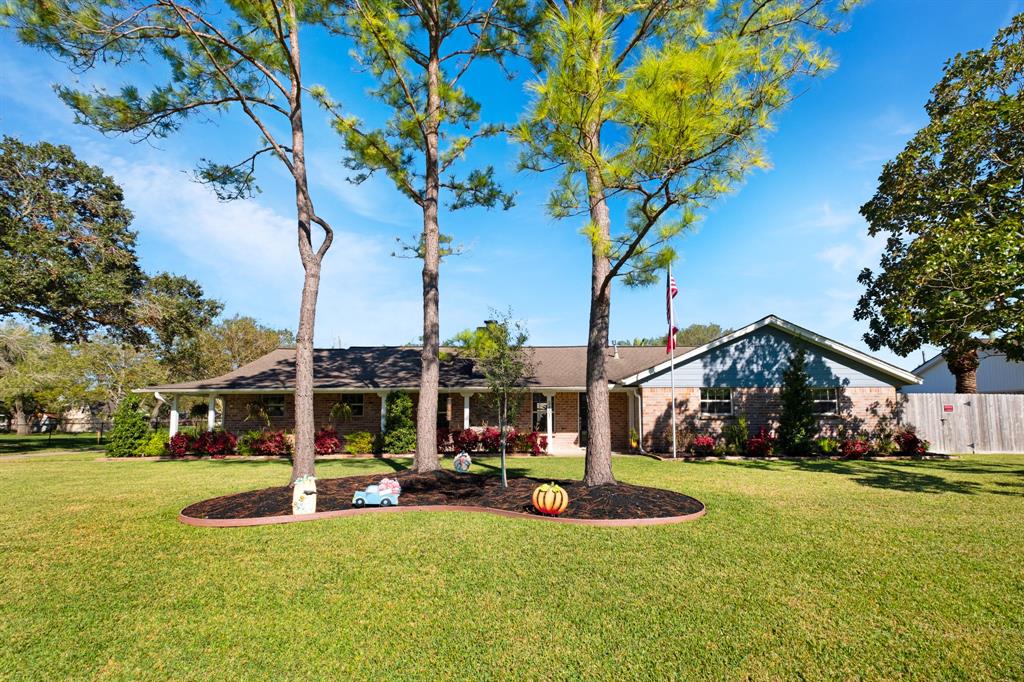 This is a single-story family home with a spacious, well-manicured front yard, mature trees, and a welcoming exterior. The house features a brick facade and an attached garage, nestled in a serene suburban setting.