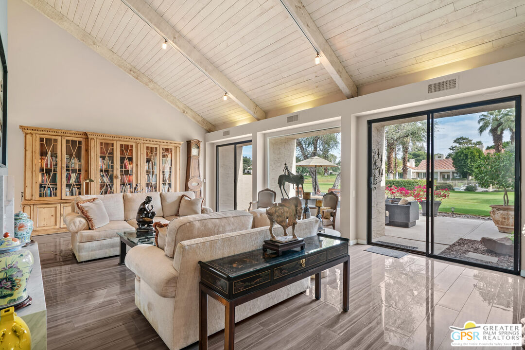 a living room with furniture large windows and wooden floor