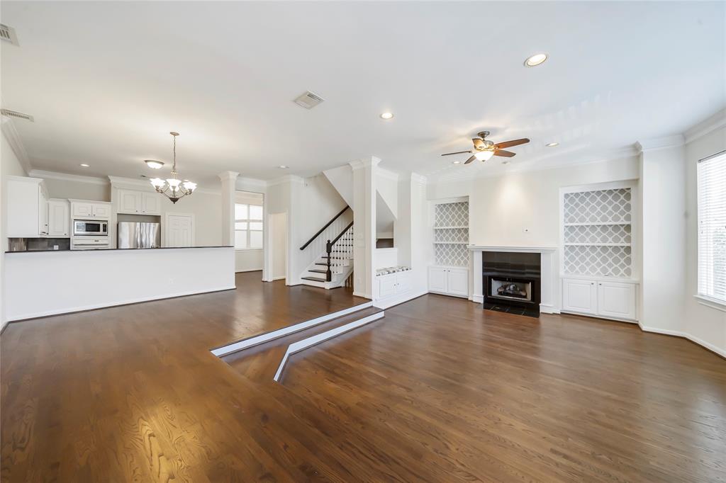 an empty room with wooden floor and kitchen view