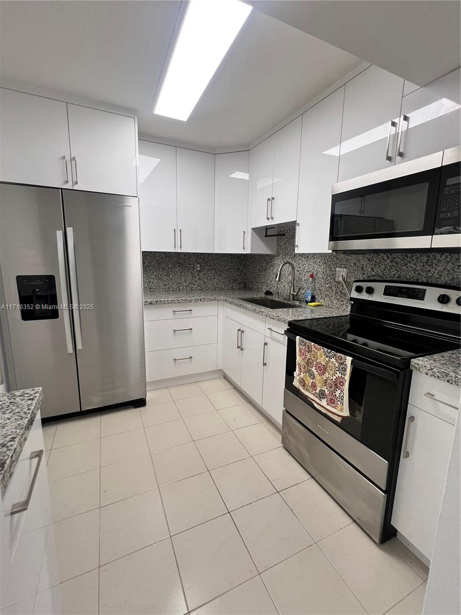 a kitchen with granite countertop a stove a sink and a refrigerator