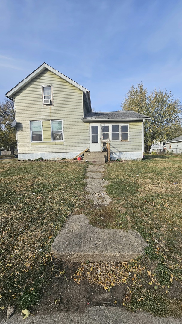 a front view of house with yard and trees in the background