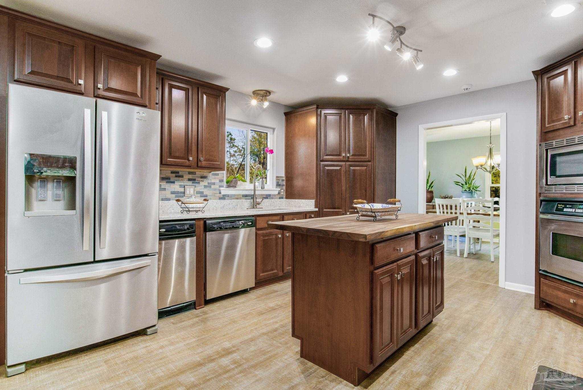 a kitchen with stainless steel appliances granite countertop a refrigerator a stove a sink and a refrigerator