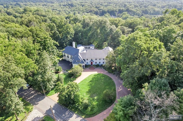 an aerial view of residential house with outdoor space and trees all around