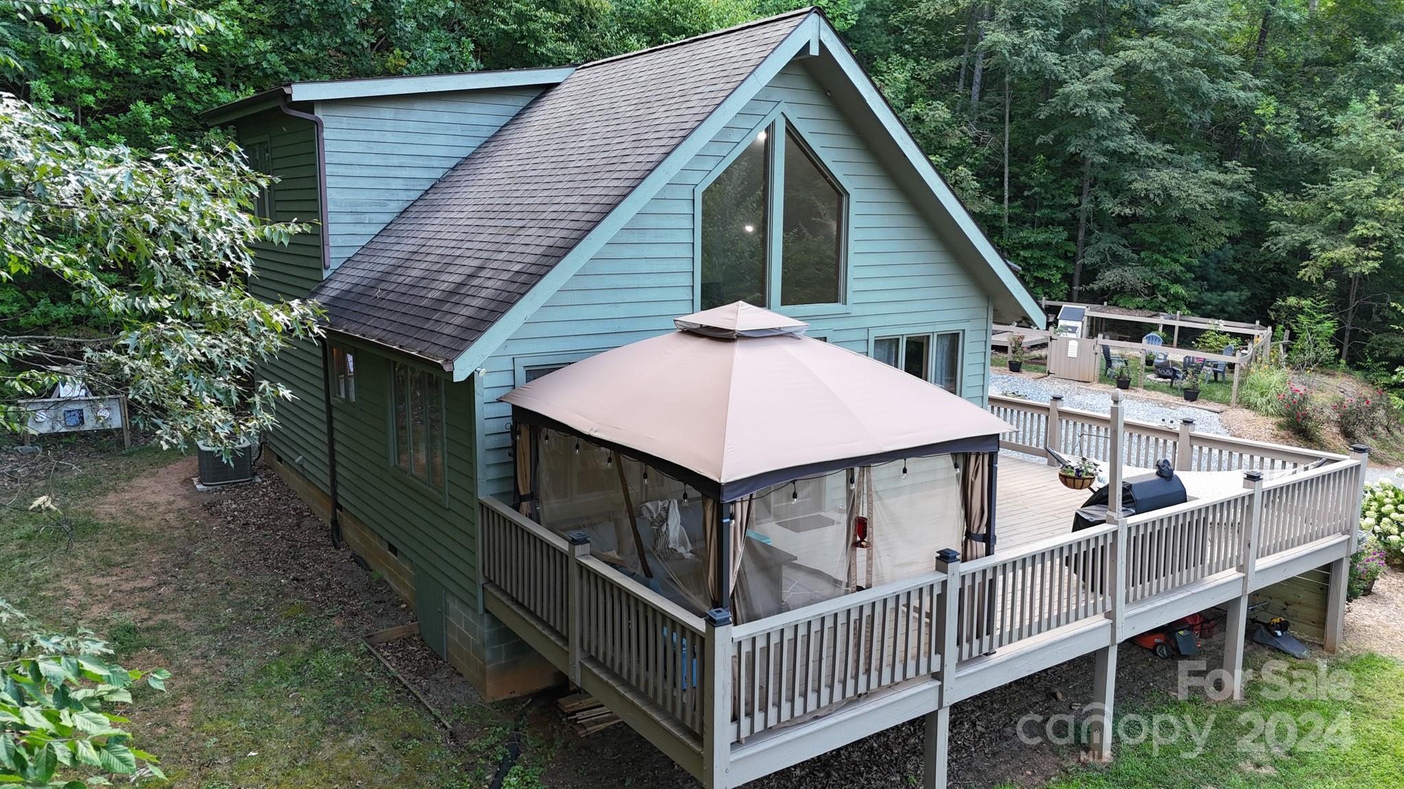 a view of house with wooden deck and backyard