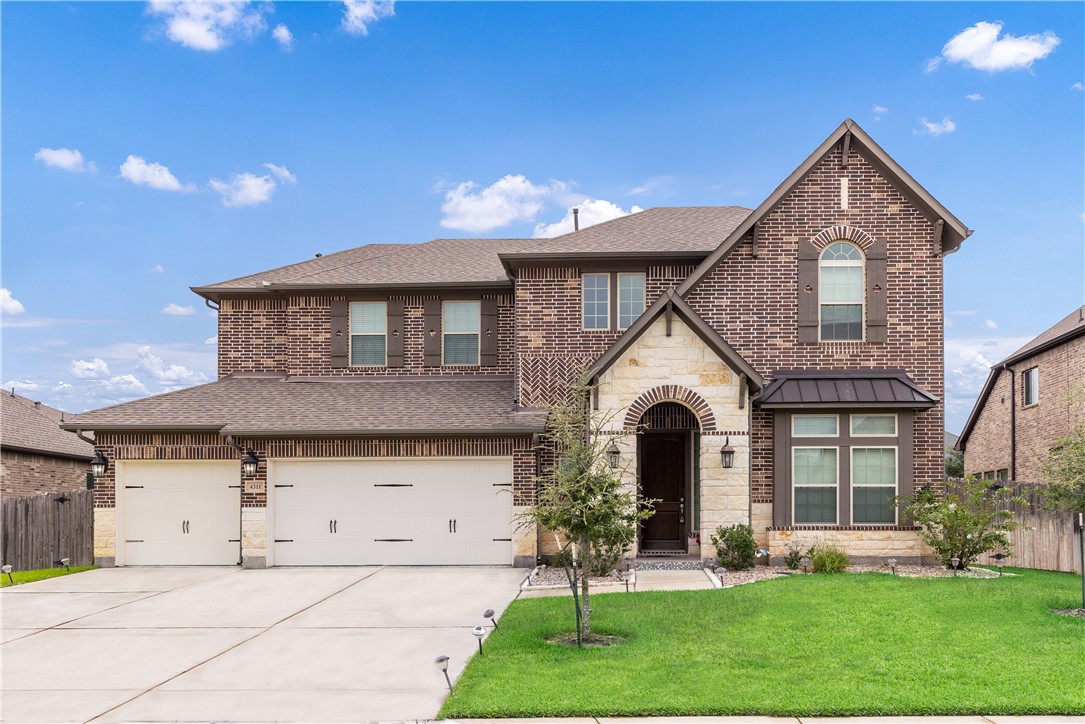 View of front of home with a front yard and a gara