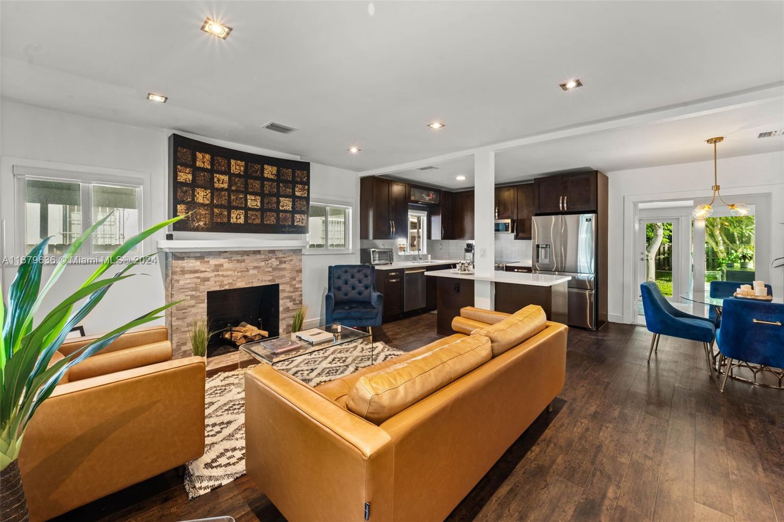 a living room with stainless steel appliances furniture a fireplace and a open kitchen view