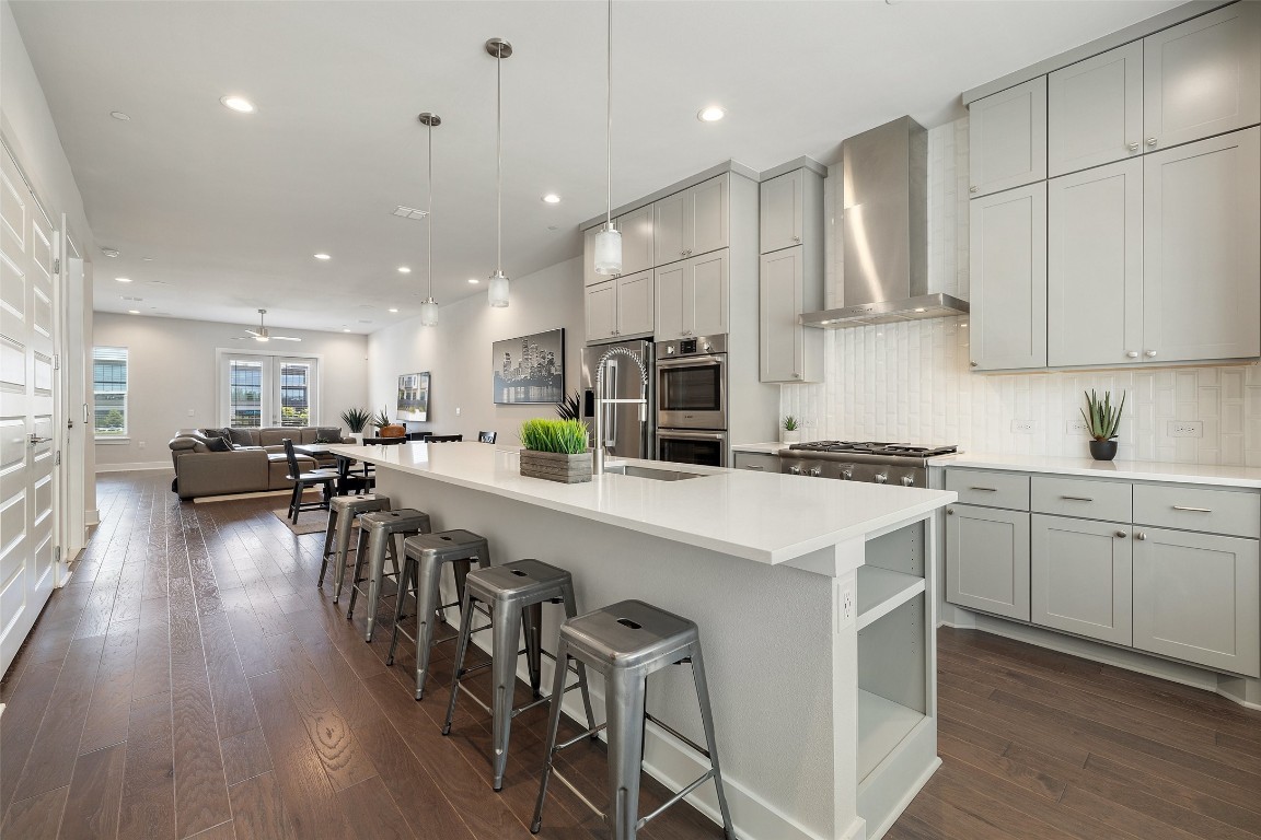 a kitchen with a sink a stove and chairs with wooden floor