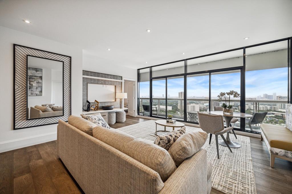 a living room with furniture large windows and wooden floor