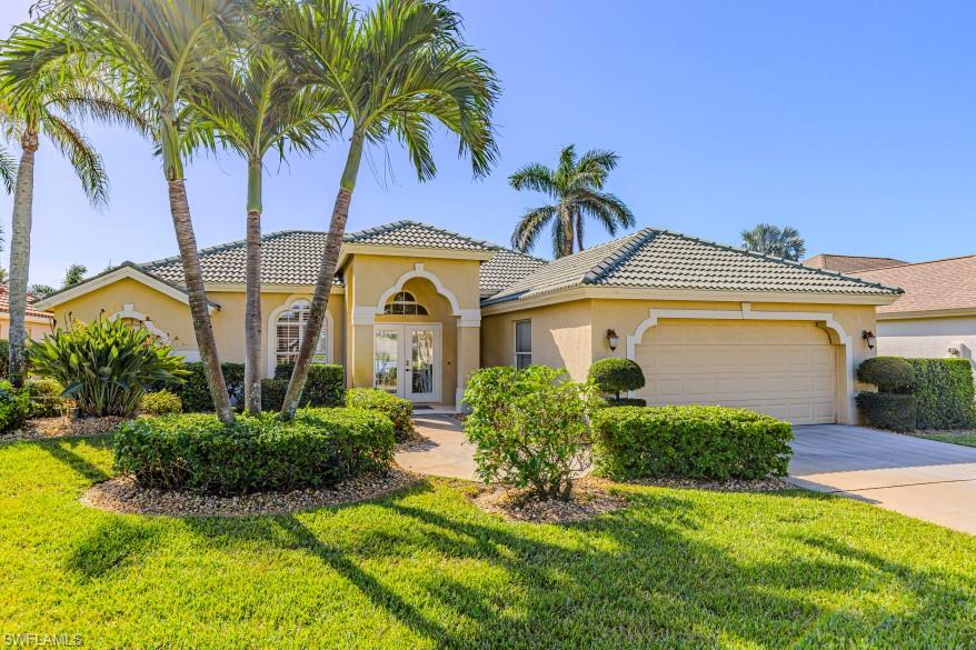 Mediterranean / spanish-style home featuring a garage, a front yard, and french doors