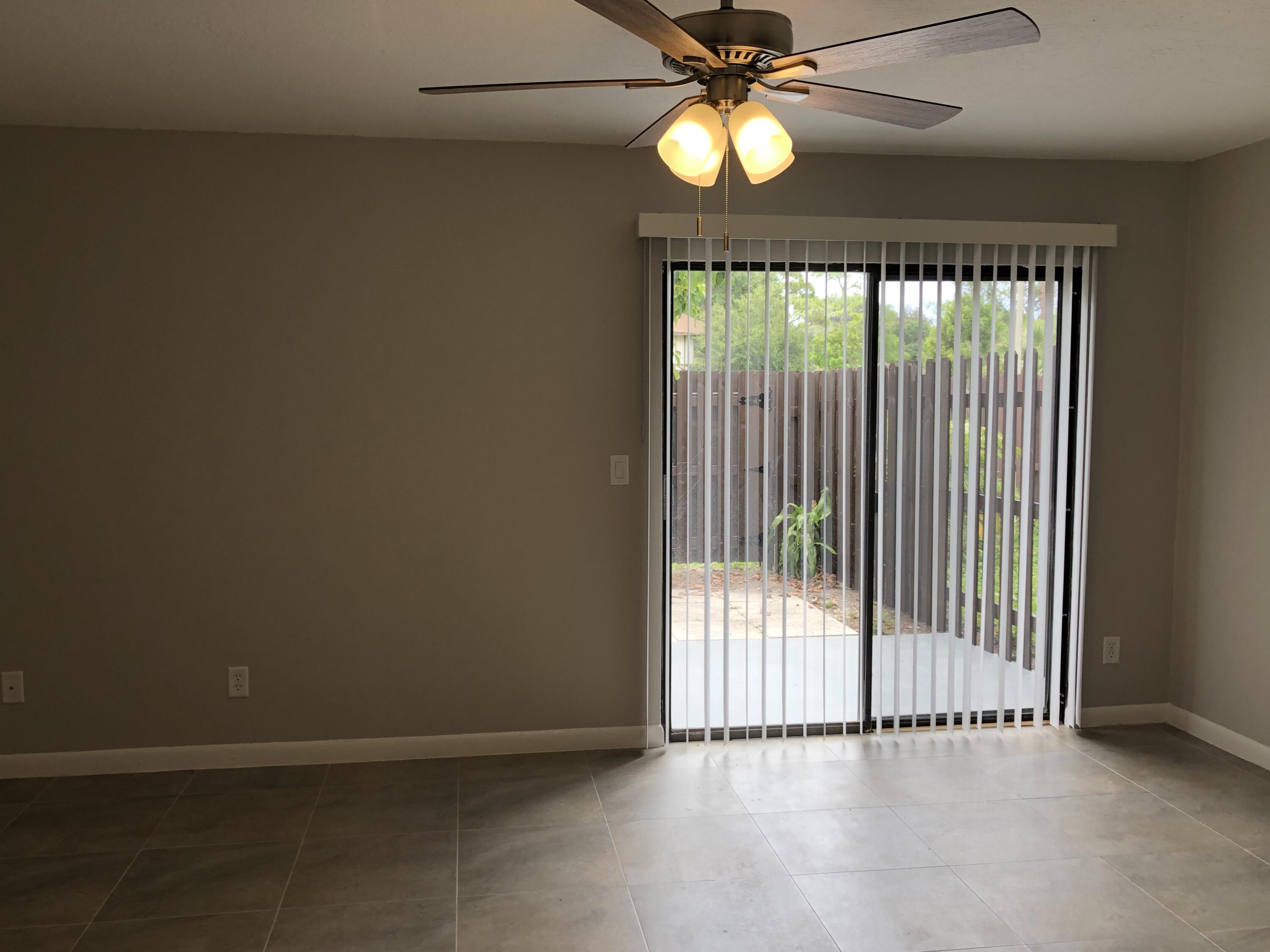 an empty room with chandelier fan and windows