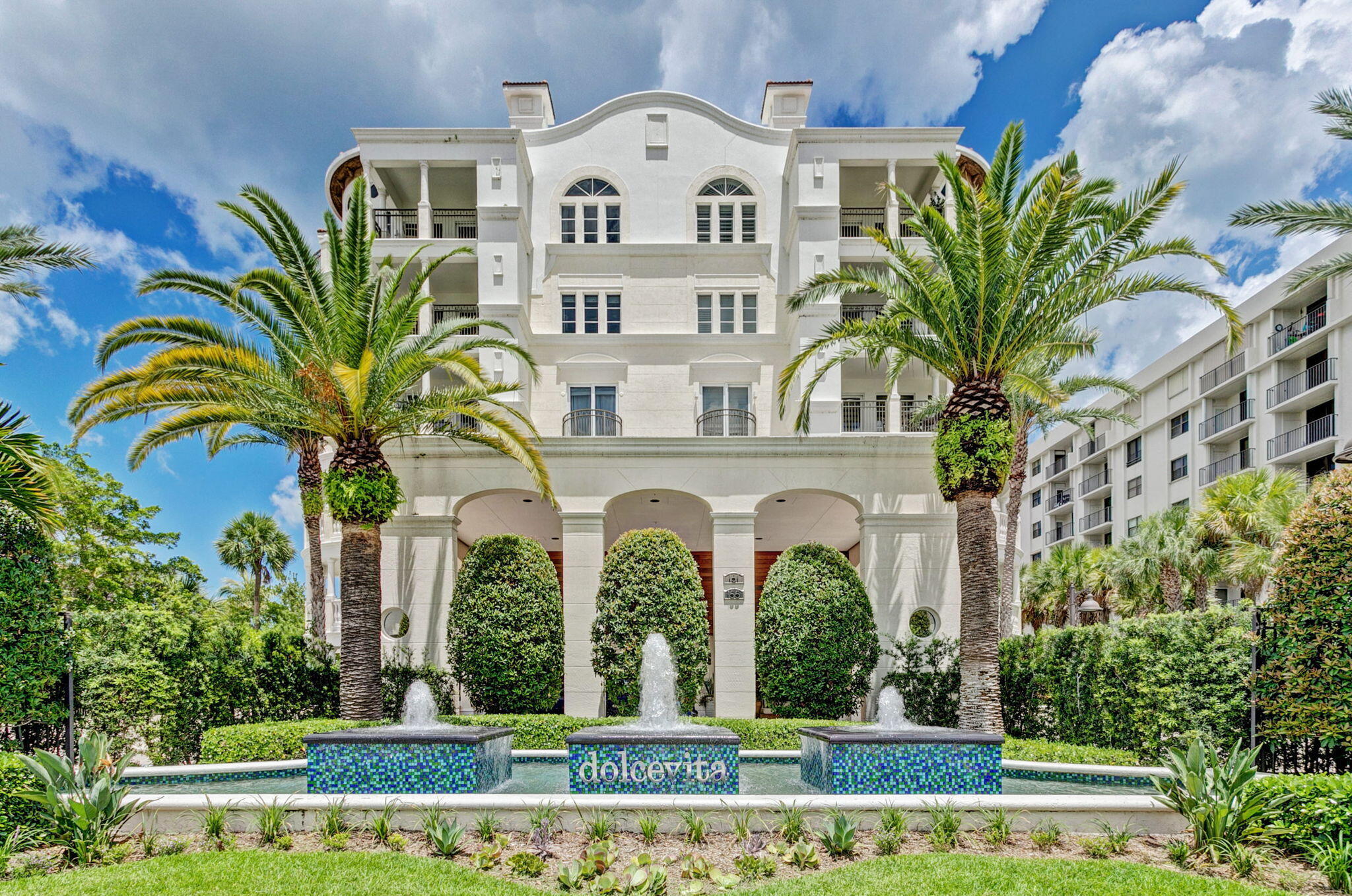 a view of a white building with a large garden and plants