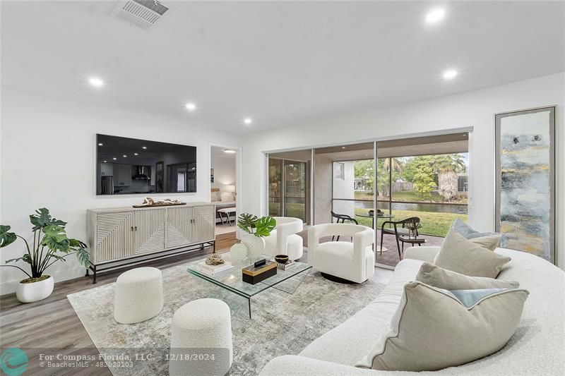 a living room with furniture flat screen tv and a large window