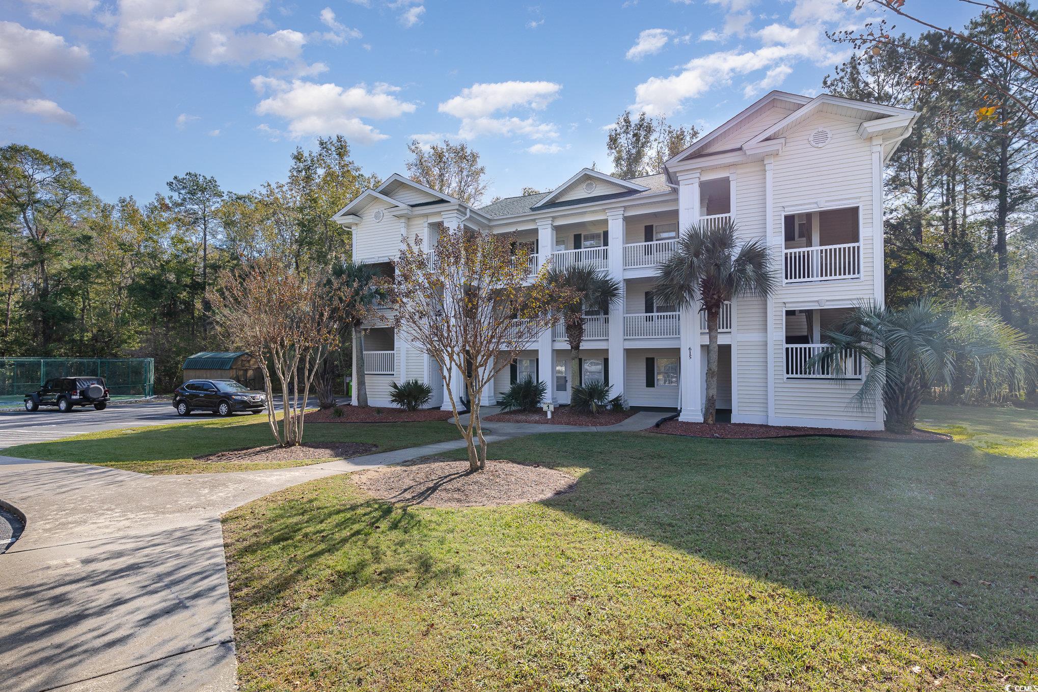 View of front facade with a balcony and a front ya