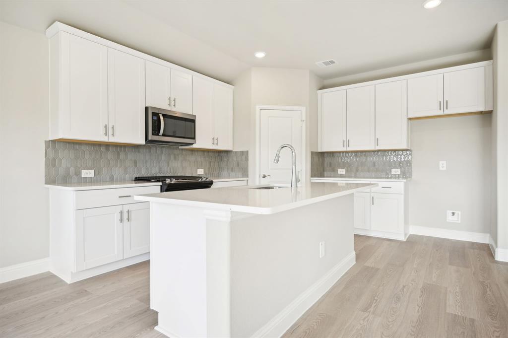 a kitchen with stainless steel appliances a sink a stove a microwave and cabinets