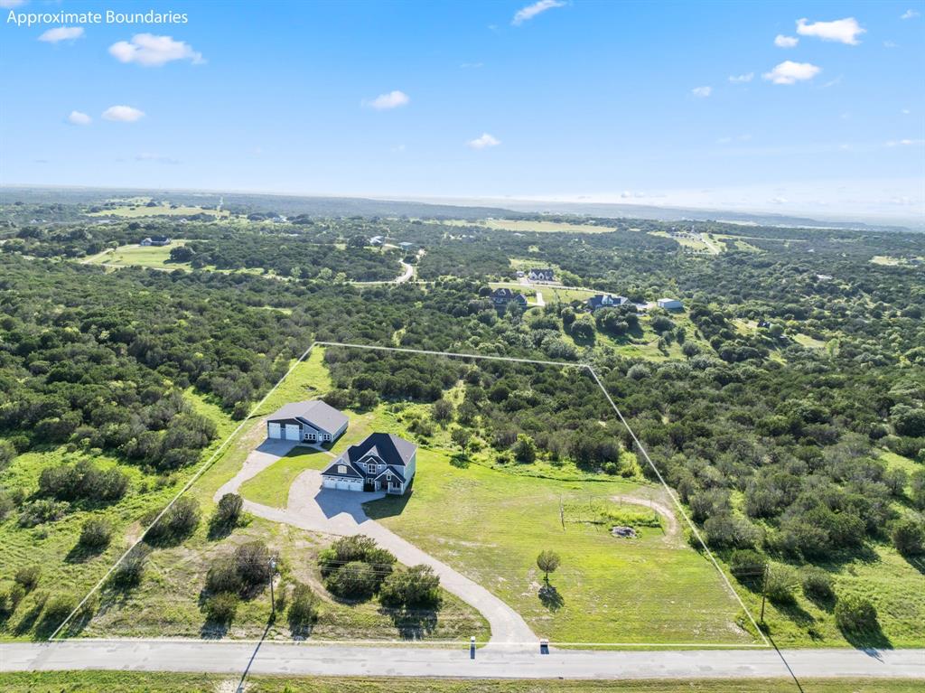 an aerial view of a residential houses with outdoor space and trees