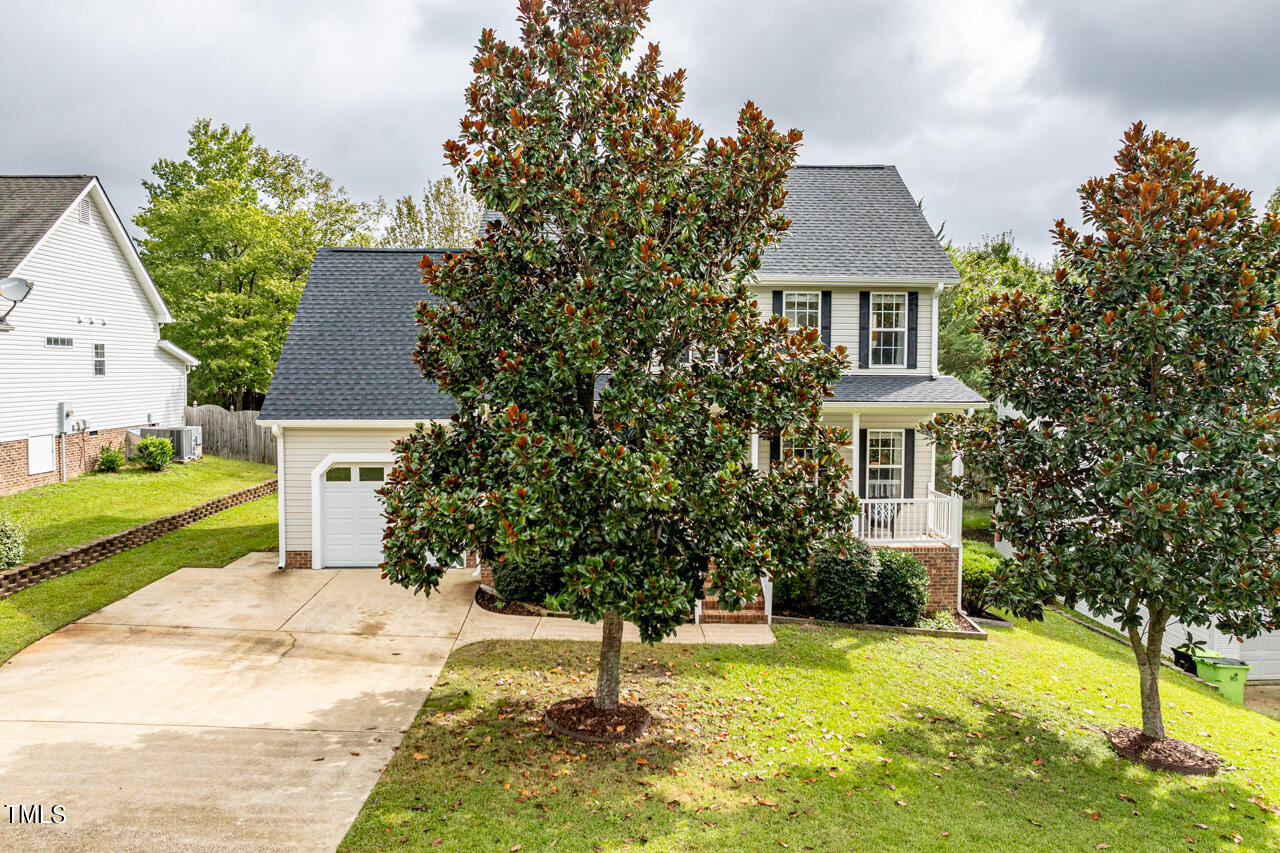 a front view of a house with a yard and trees