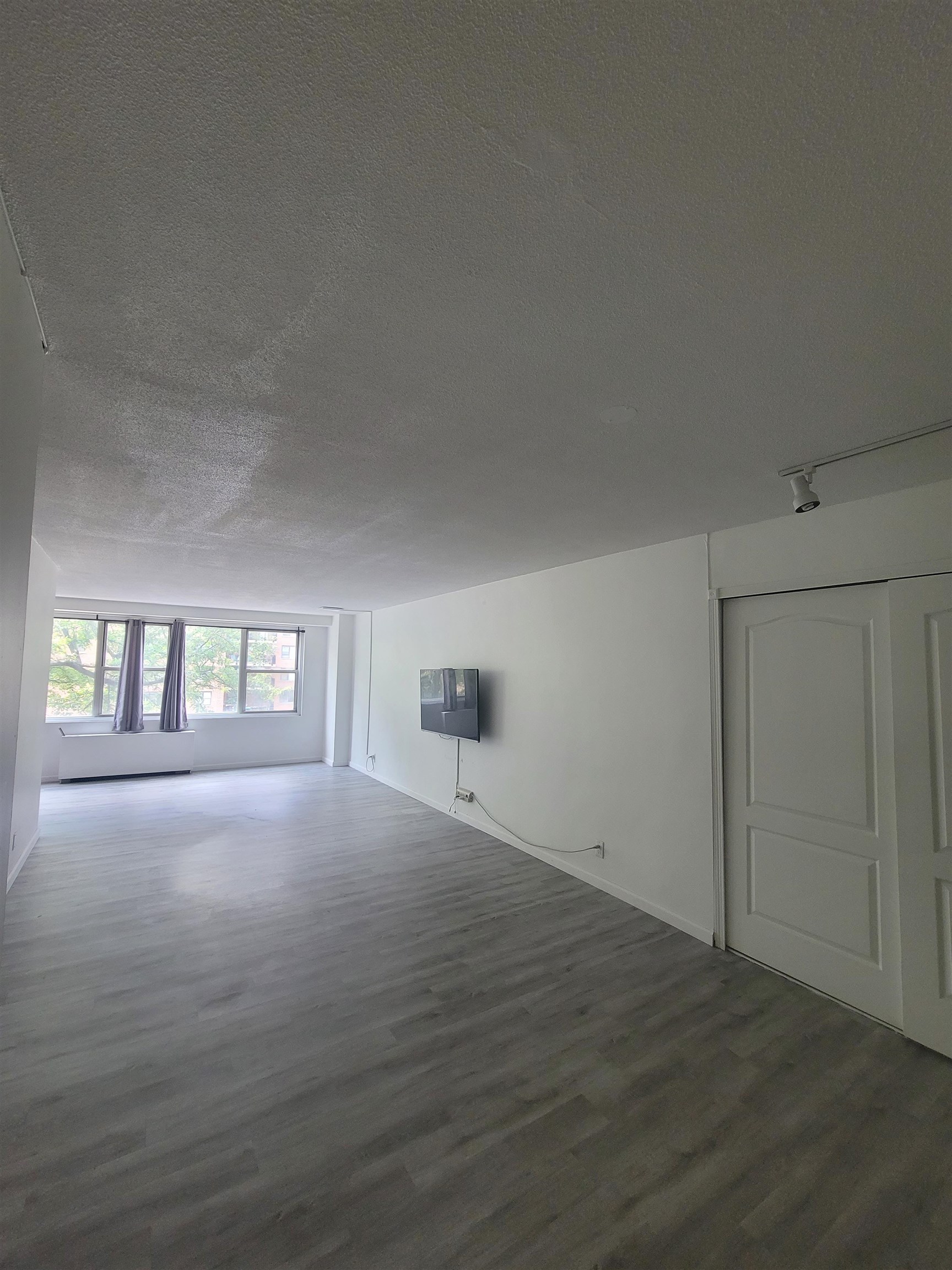 an empty room with wooden floor and windows