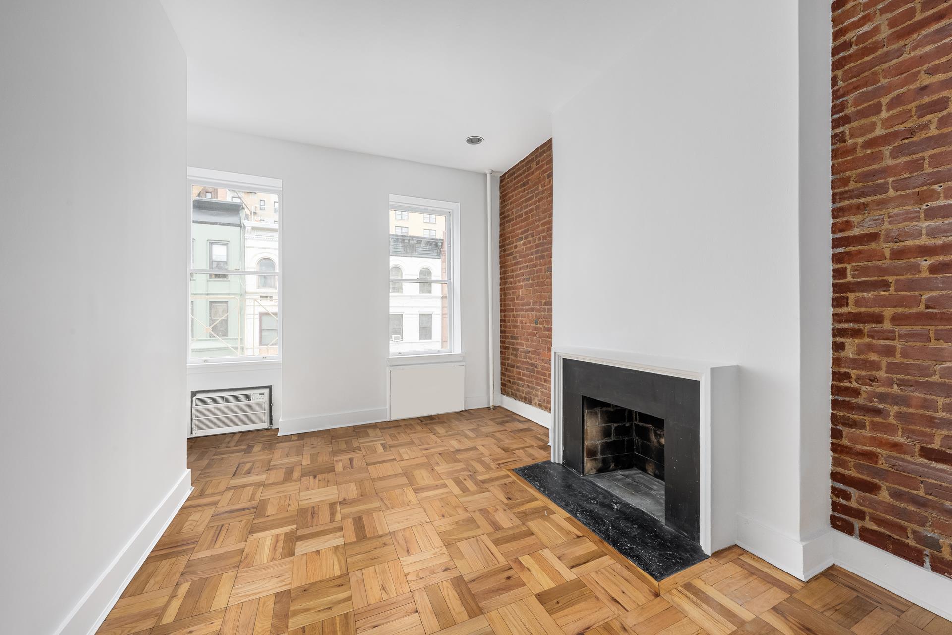 a view of an empty room with window and fire place