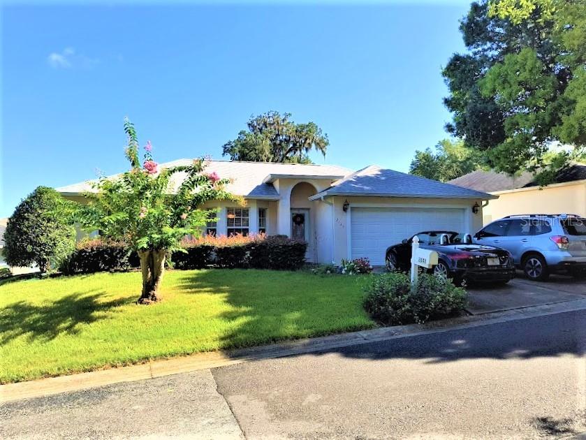 a front view of a house with garden and trees