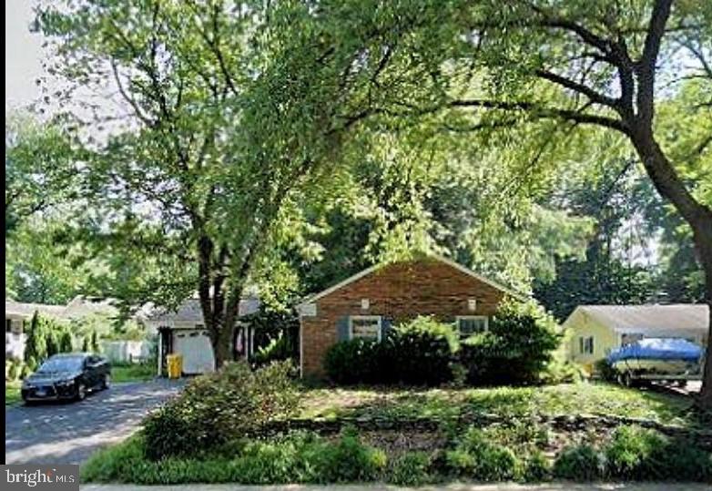 a front view of a house with a yard and large trees