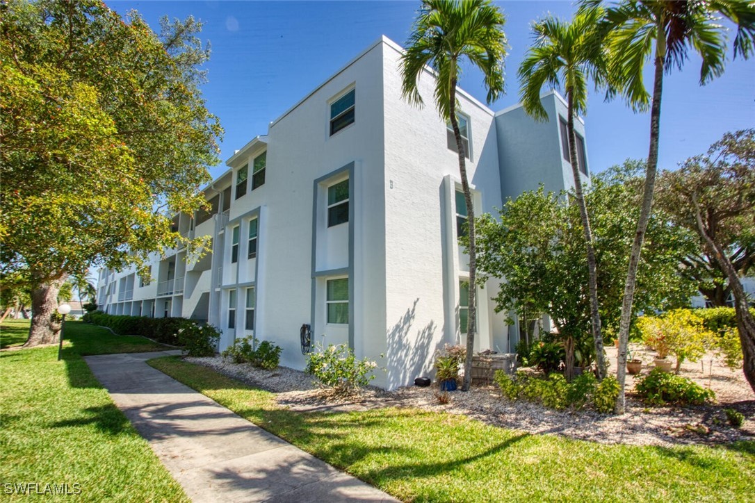 a view of a white house with a yard and coconut trees