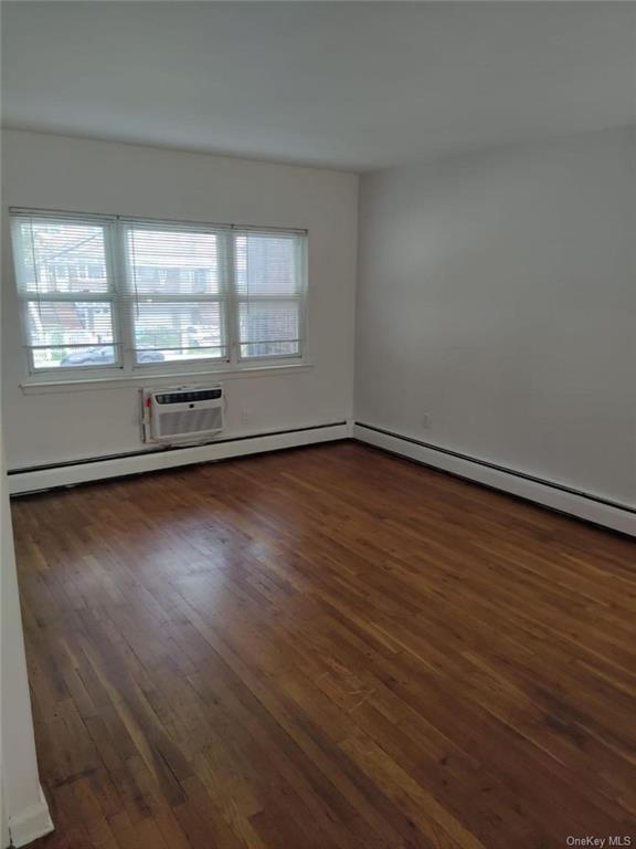 Unfurnished room featuring dark hardwood / wood-style flooring and a wall unit AC