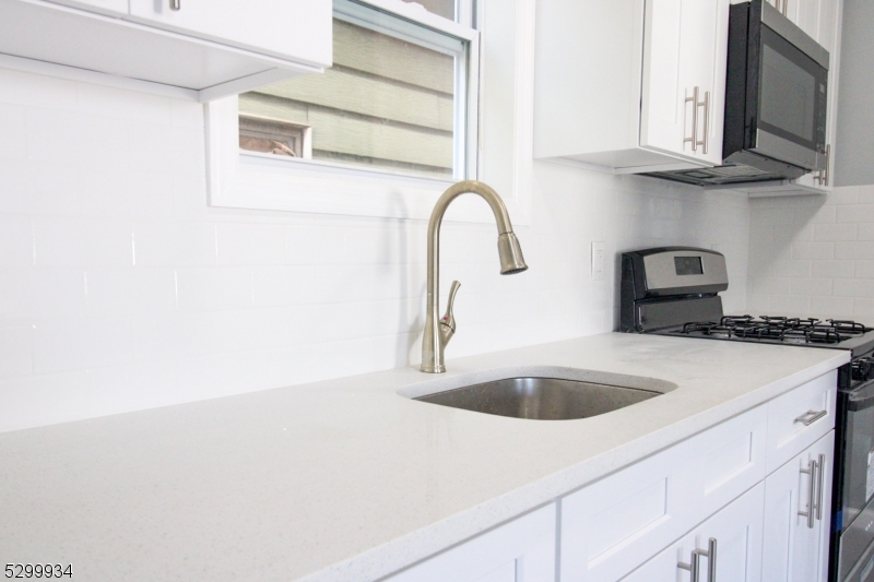 a kitchen with stainless steel appliances granite countertop a sink and a white cabinets