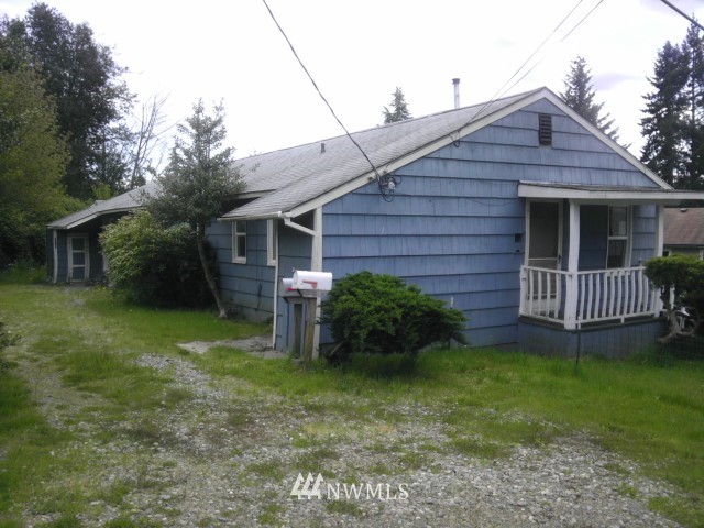 a view of a house with a yard plants and large tree