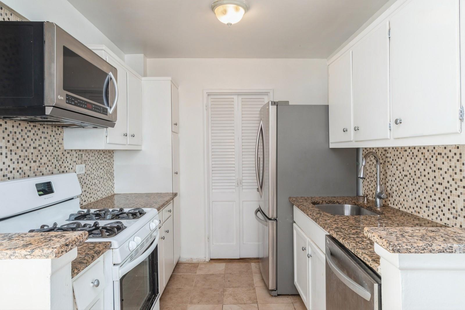 Kitchen with sink, decorative backsplash, dark stone countertops, appliances with stainless steel finishes, and white cabinetry