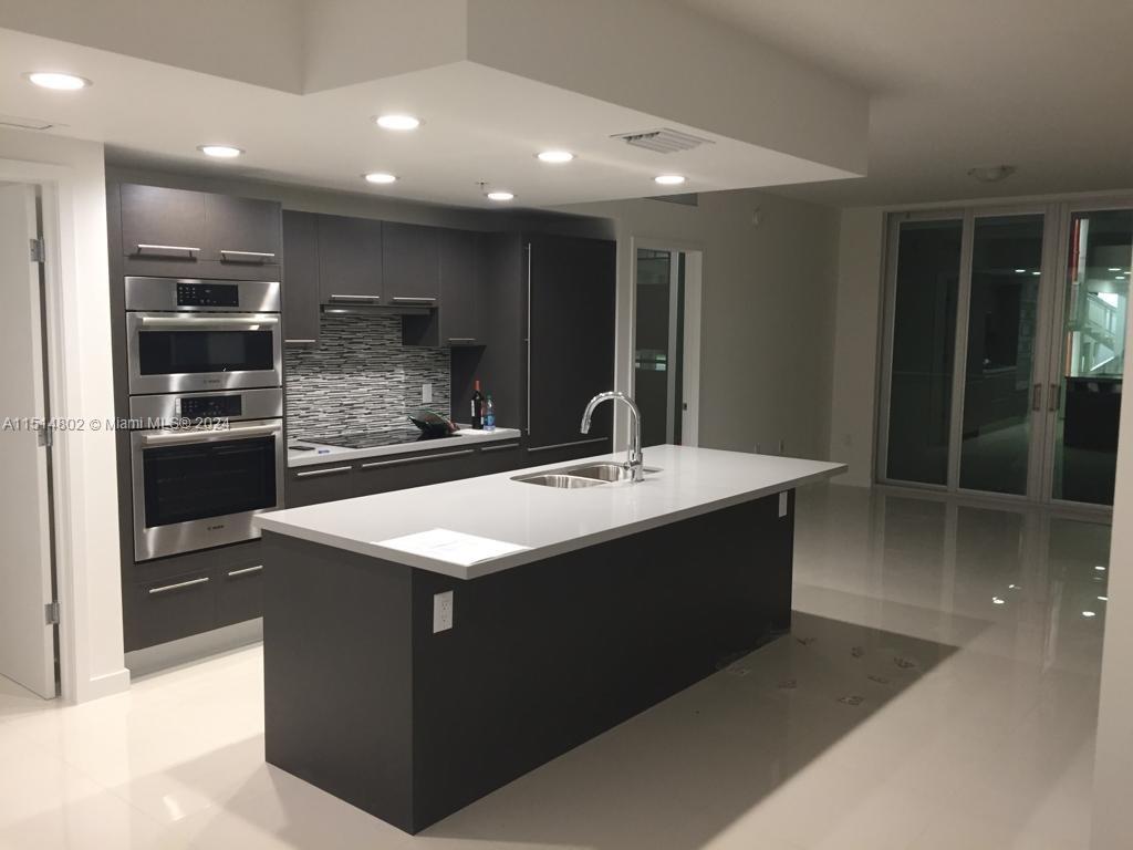 a kitchen with kitchen island sink and refrigerator