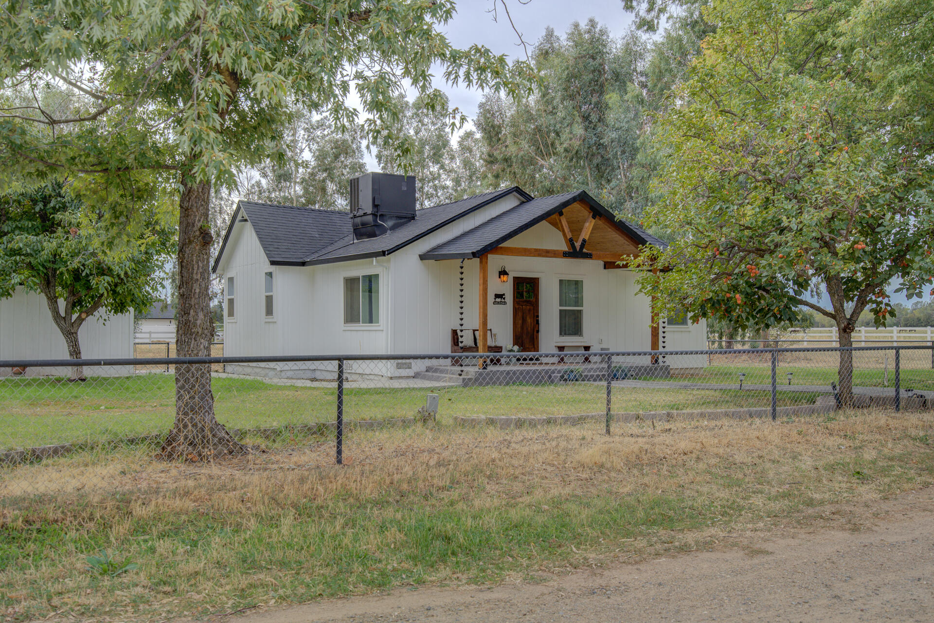 a backyard of a house with wooden fence and large trees