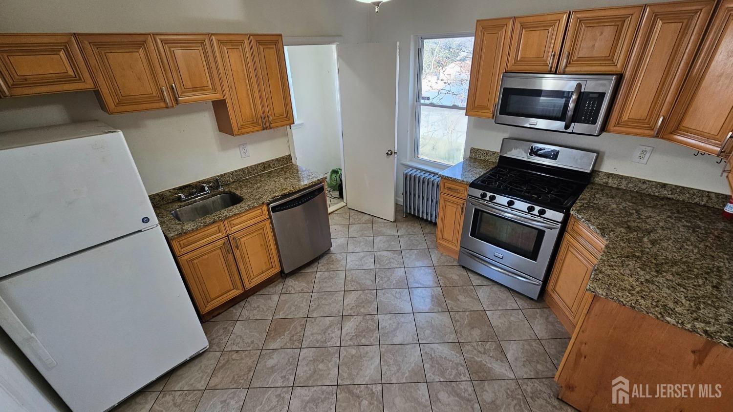 a kitchen with granite countertop a stove a microwave a sink and cabinets