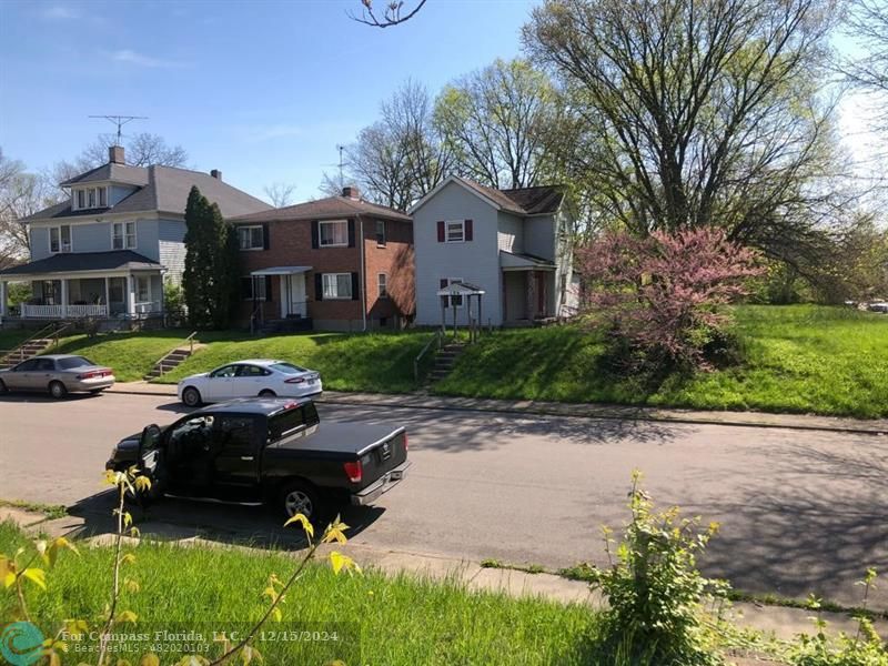 a car parked in front of a brick house with a large trees