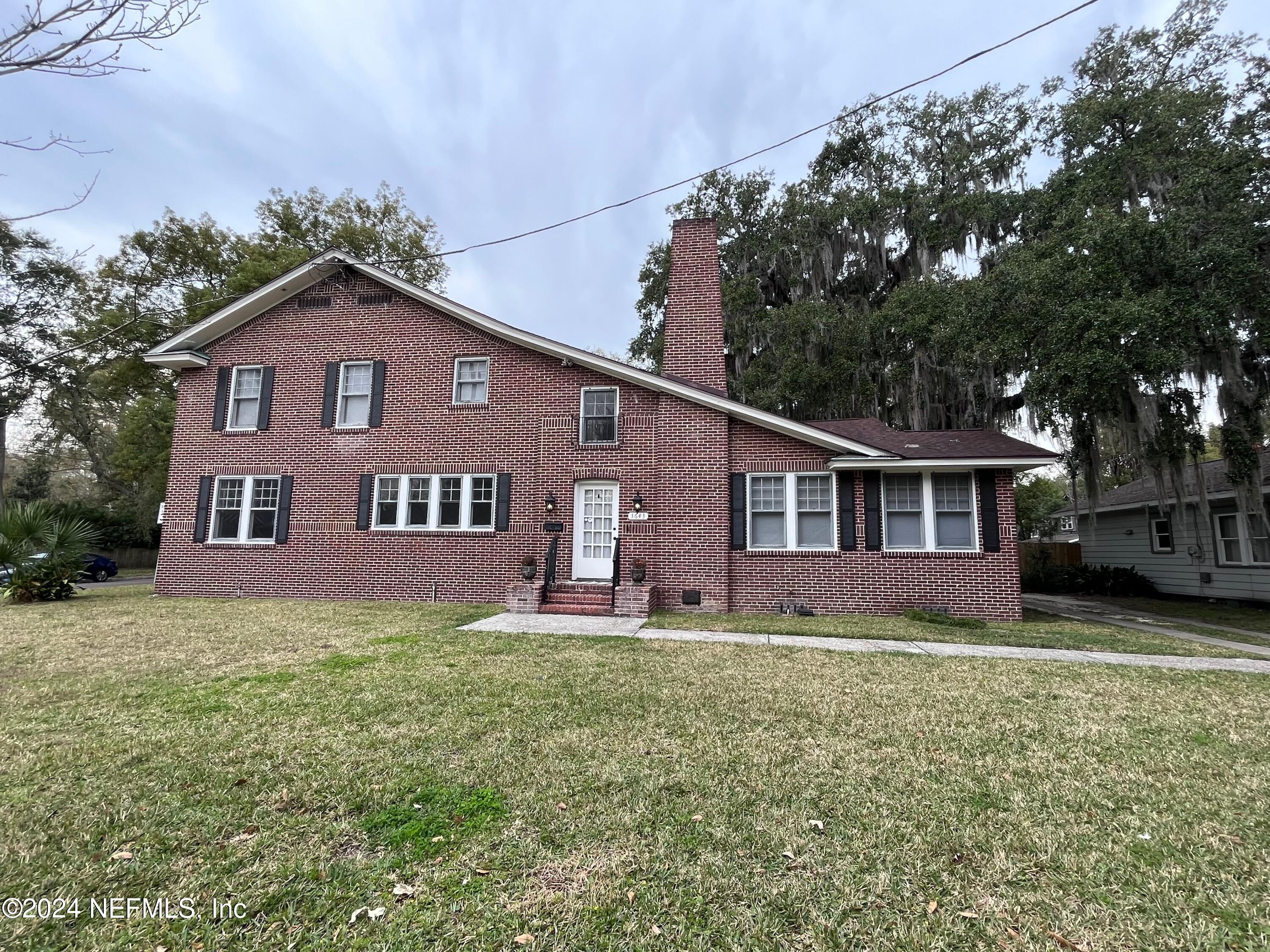 a house that is sitting in the grass with large trees