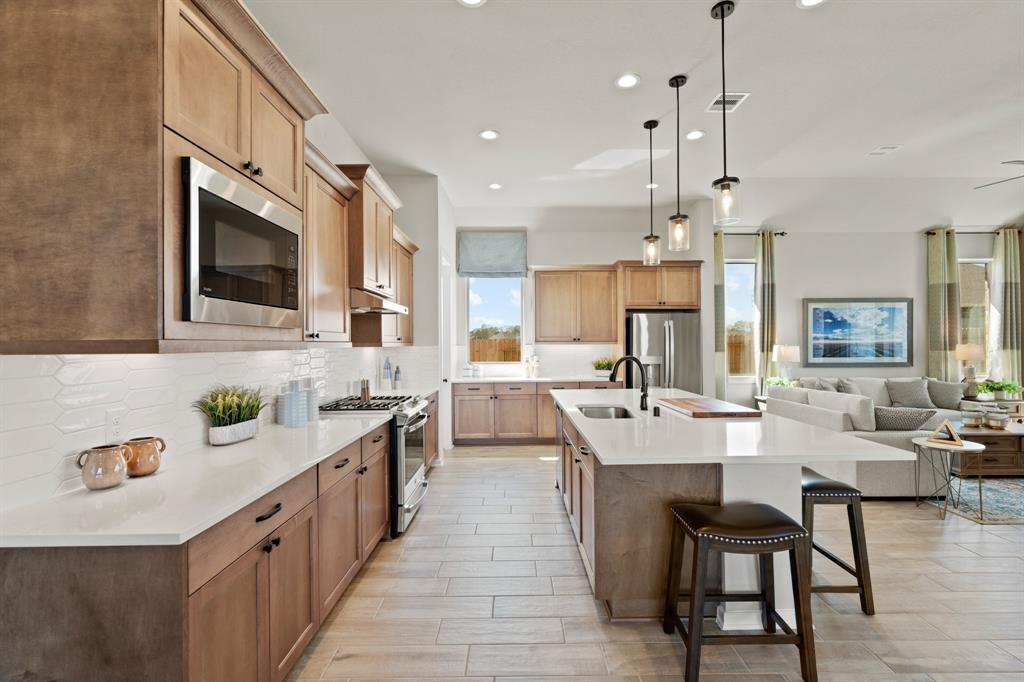 a large kitchen with stainless steel appliances kitchen island granite countertop a sink and a refrigerator