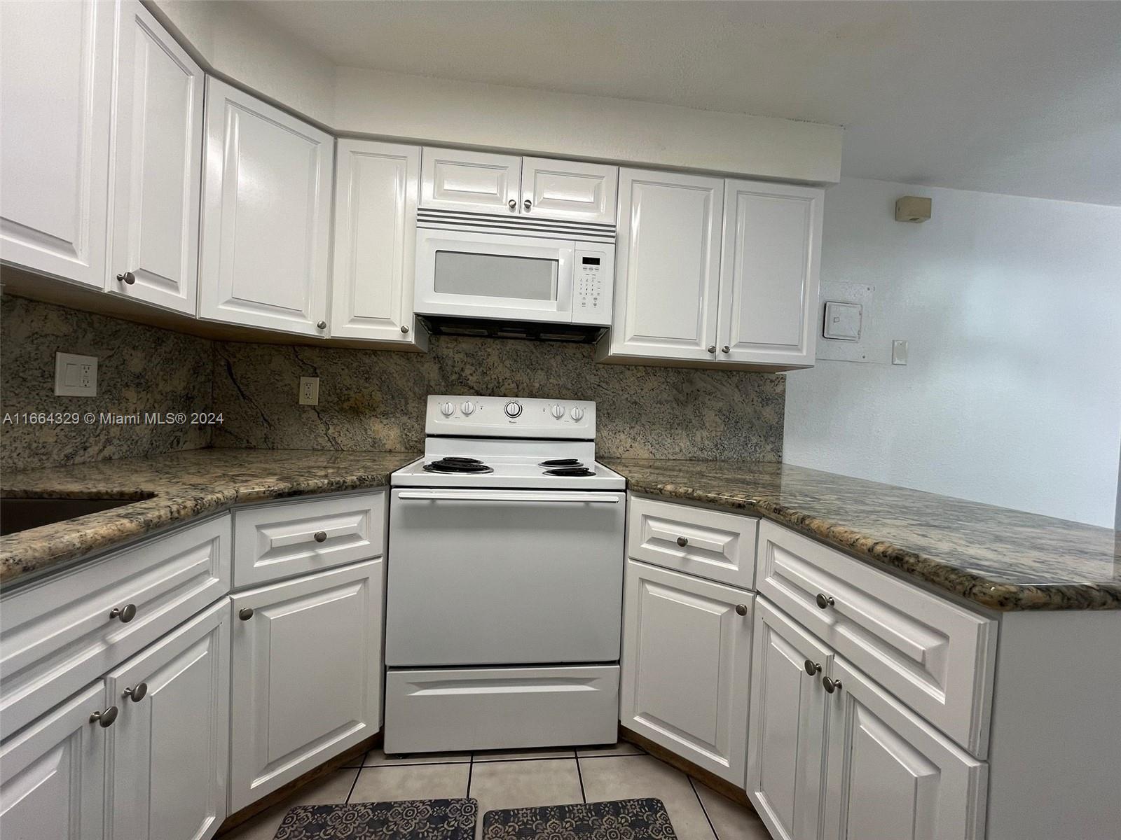 a kitchen with granite countertop white cabinets and white appliances