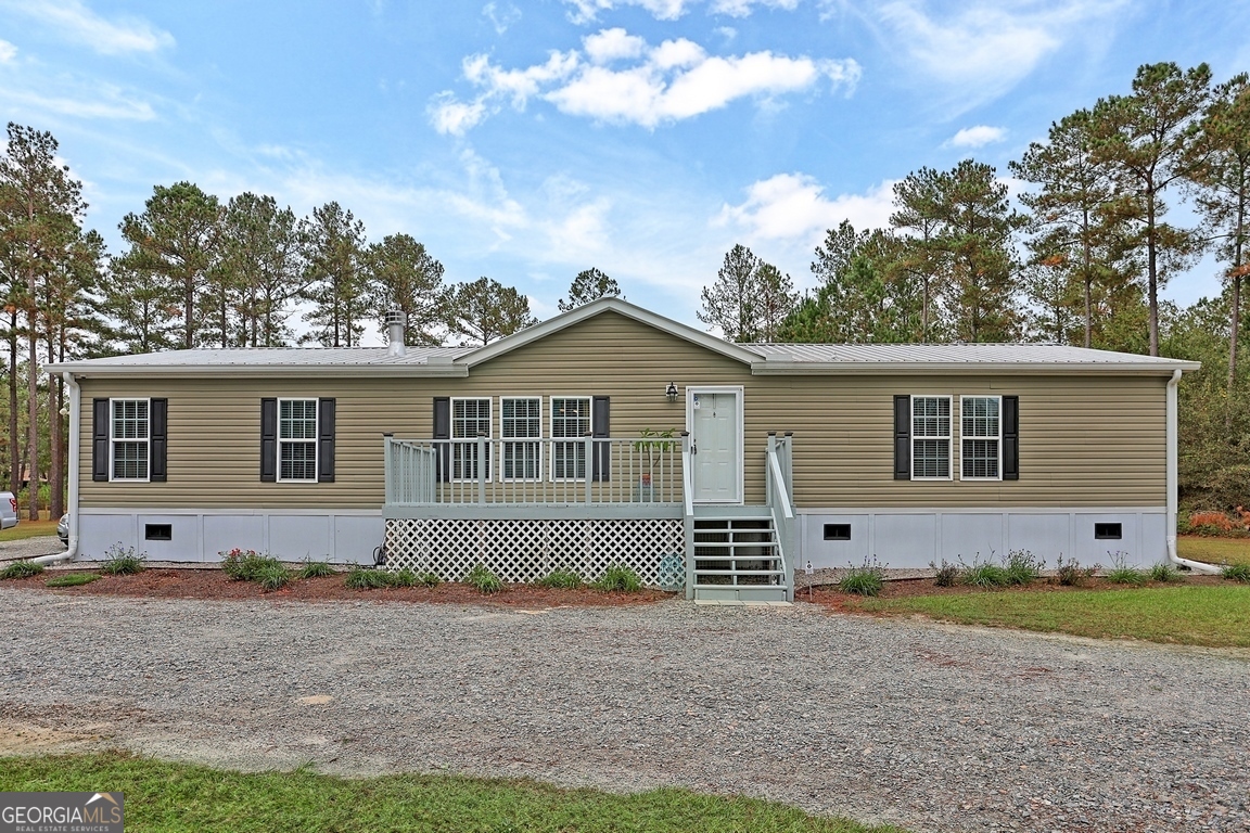 a front view of house with yard and trees in the background