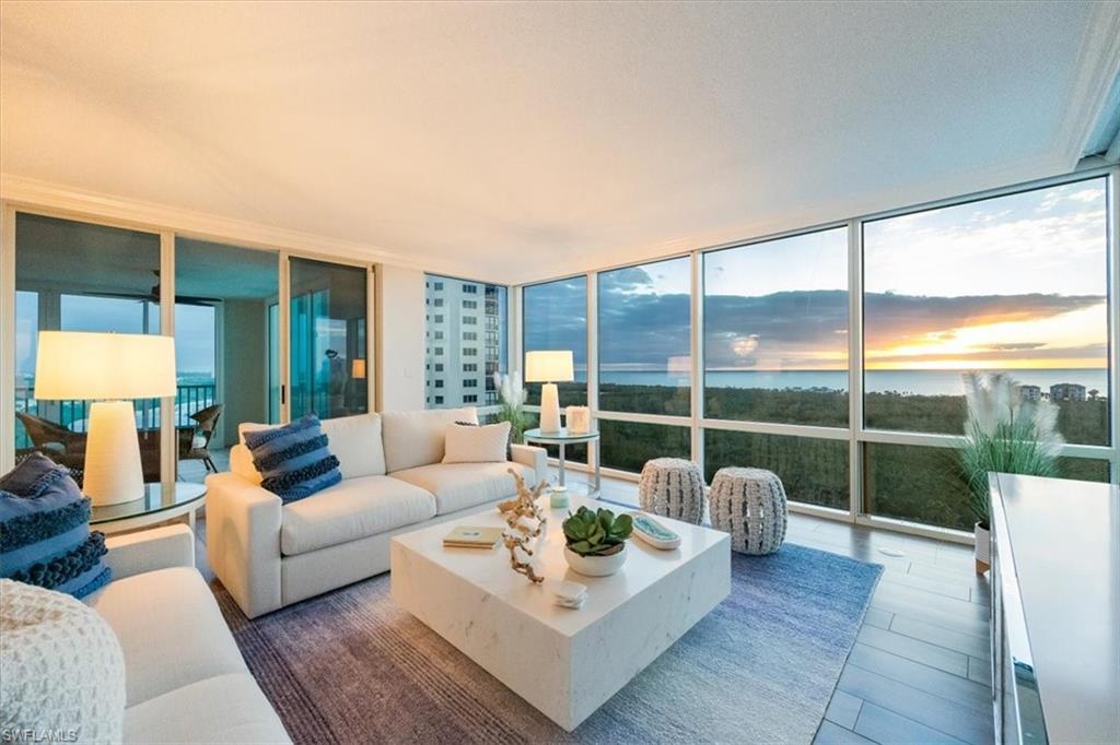 a living room with furniture a rug and a floor to ceiling window