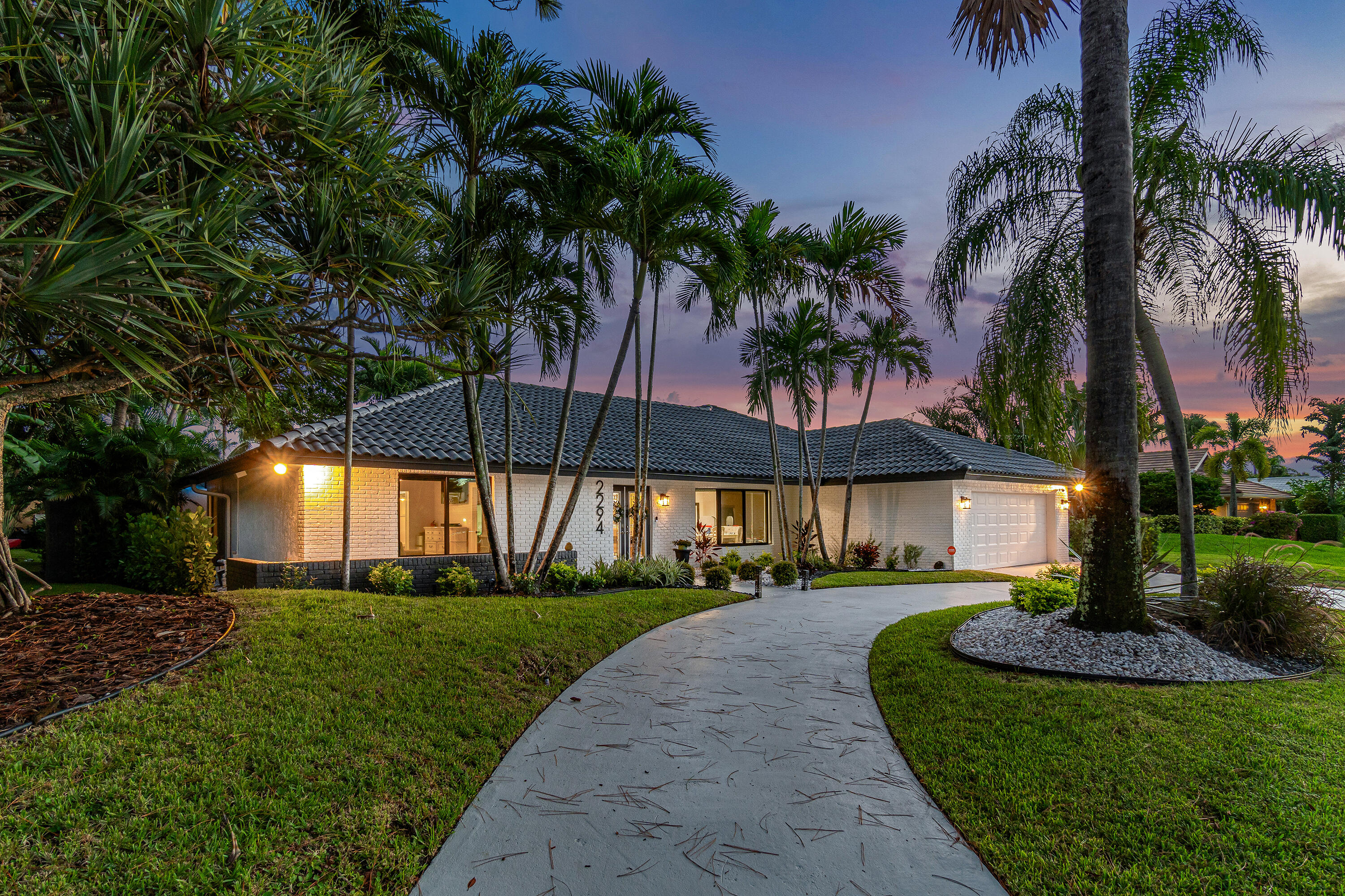 front view of house with a yard and palm trees