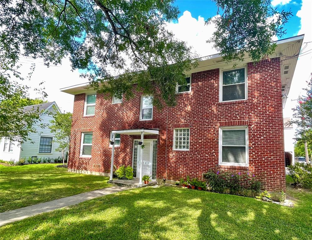 a brick house with a large tree in front of a house