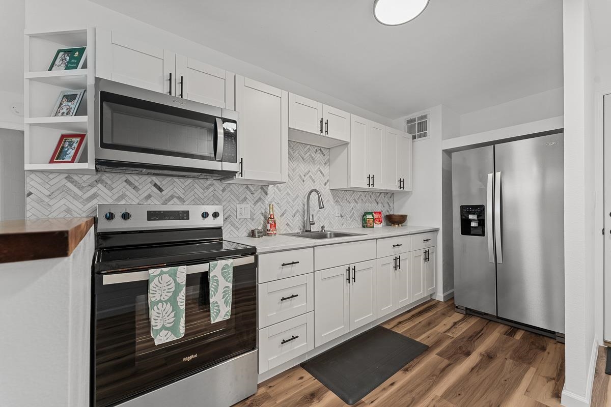 a kitchen with stainless steel appliances a stove microwave and sink