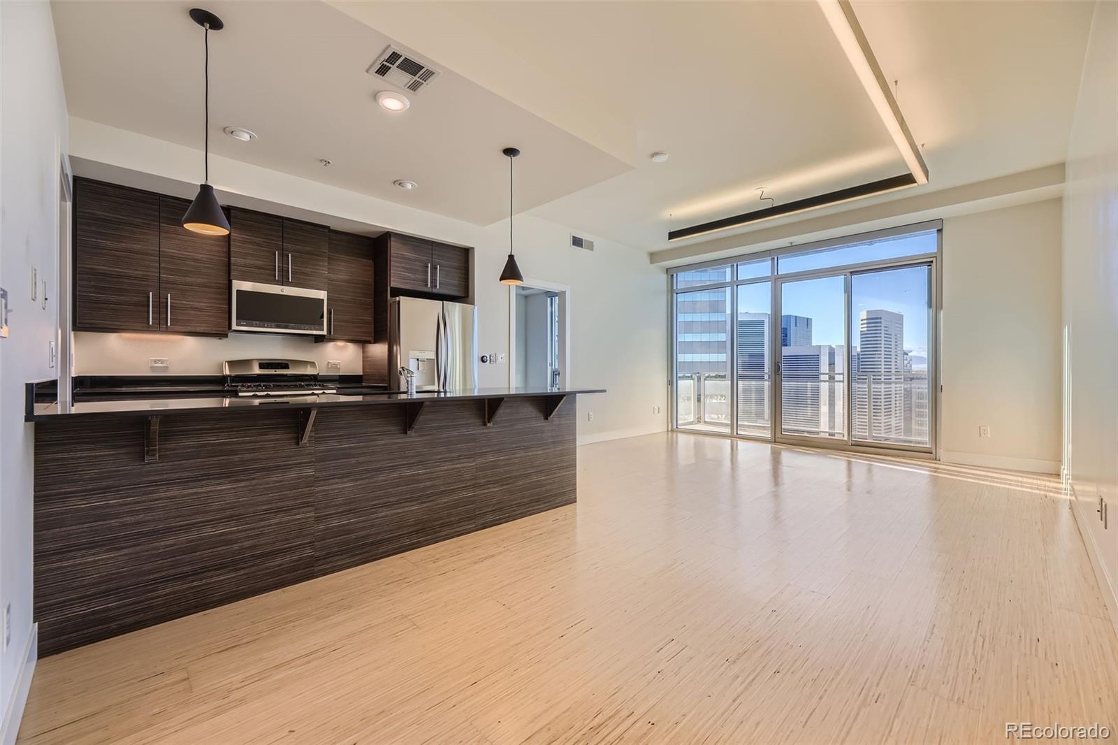 a view of kitchen with stainless steel appliances wooden floor and large window