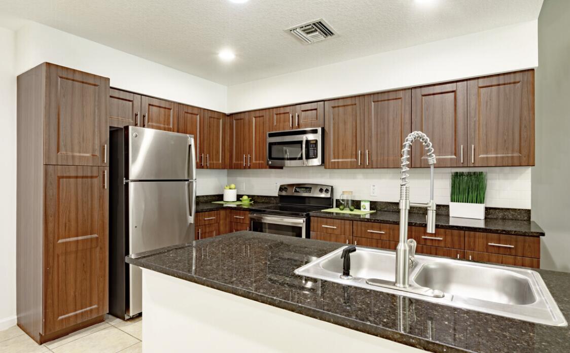 a kitchen with granite countertop a refrigerator a stove a sink and dishwasher