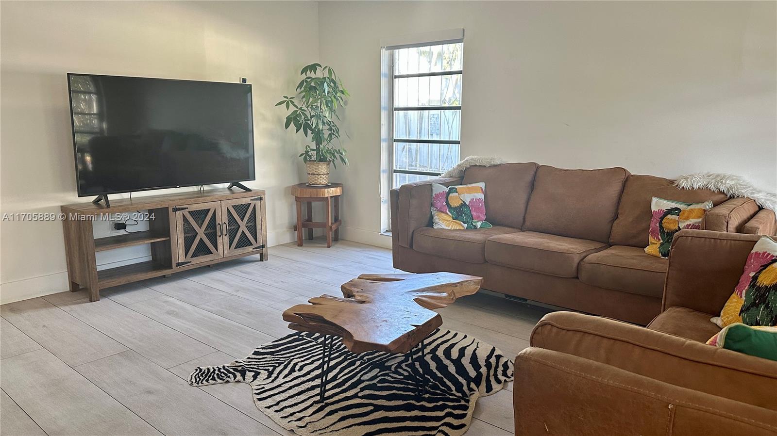 a living room with furniture a flat screen tv and a window