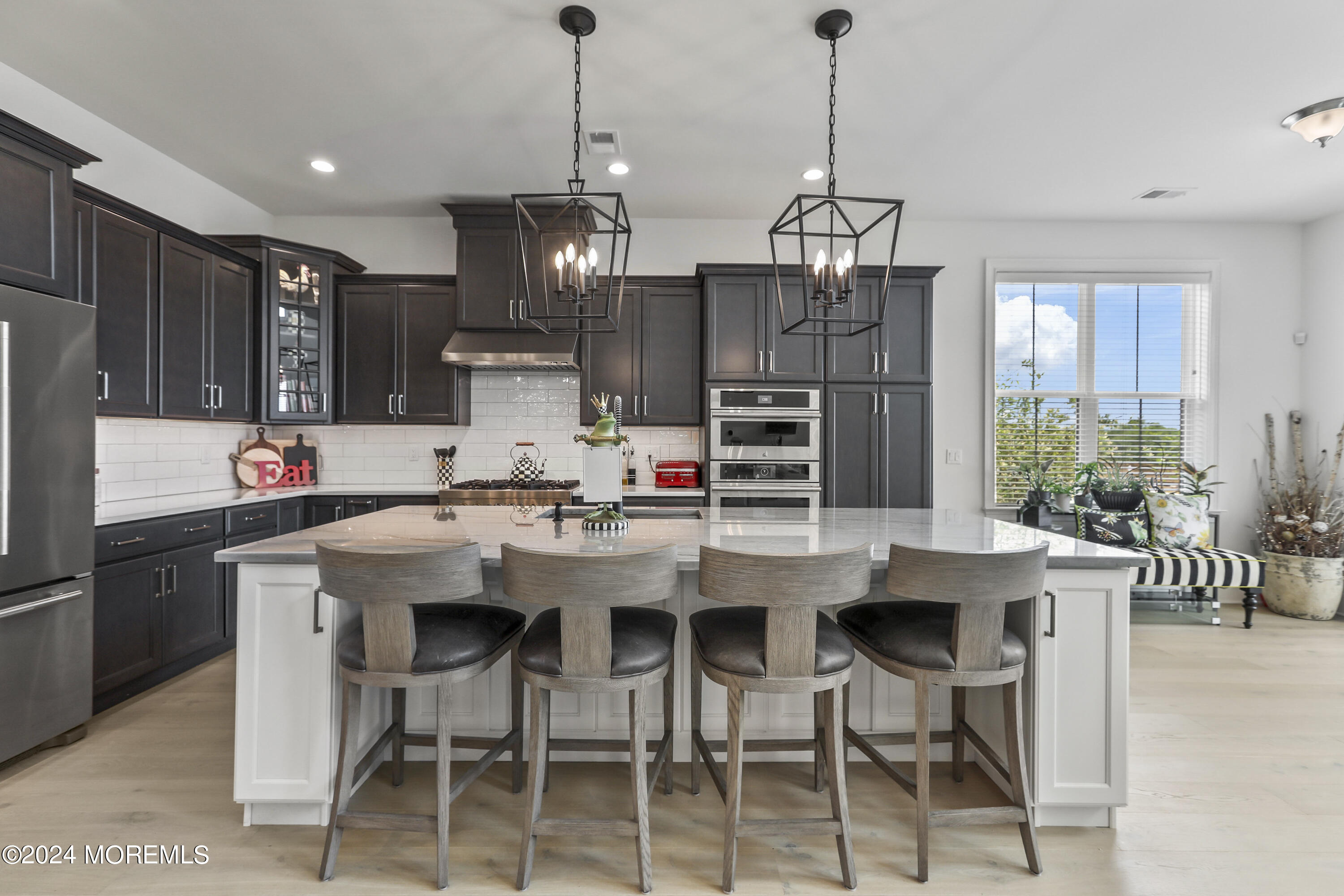 a kitchen with stainless steel appliances kitchen island granite countertop a dining table chairs and white cabinets